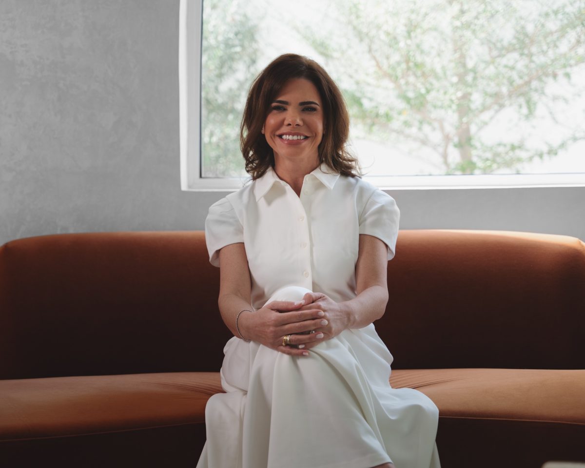 Dr. Lionella Moraes smiling, seated on a terracotta sofa
